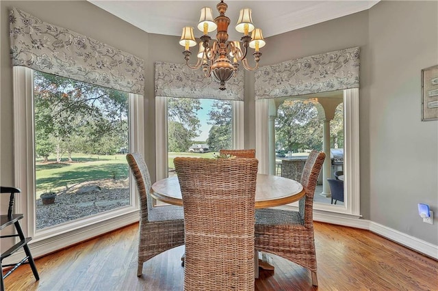 dining space featuring a chandelier, healthy amount of natural light, wood finished floors, baseboards, and ornamental molding