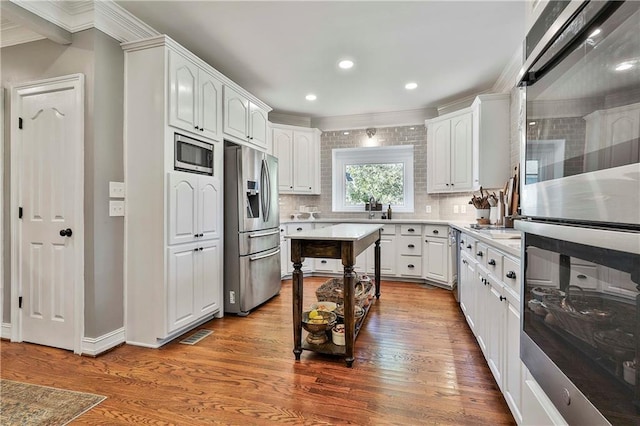 kitchen featuring appliances with stainless steel finishes, ornamental molding, light countertops, white cabinetry, and recessed lighting