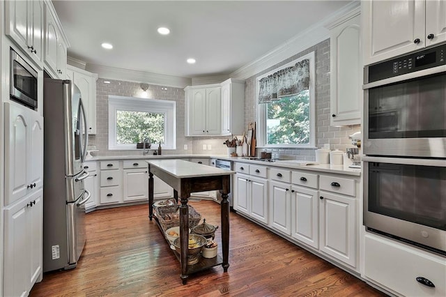 kitchen featuring stainless steel appliances, ornamental molding, decorative backsplash, healthy amount of natural light, and recessed lighting