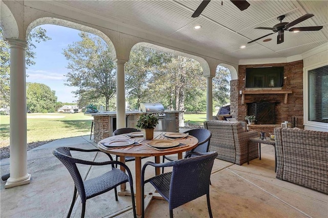 view of patio featuring exterior kitchen, ceiling fan, grilling area, outdoor dining area, and an outdoor living space with a fireplace