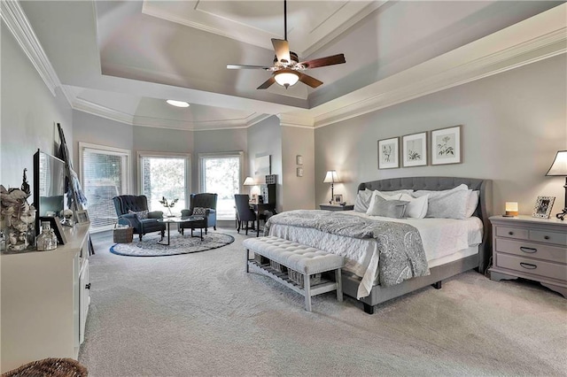 bedroom with a tray ceiling, light colored carpet, crown molding, and ceiling fan