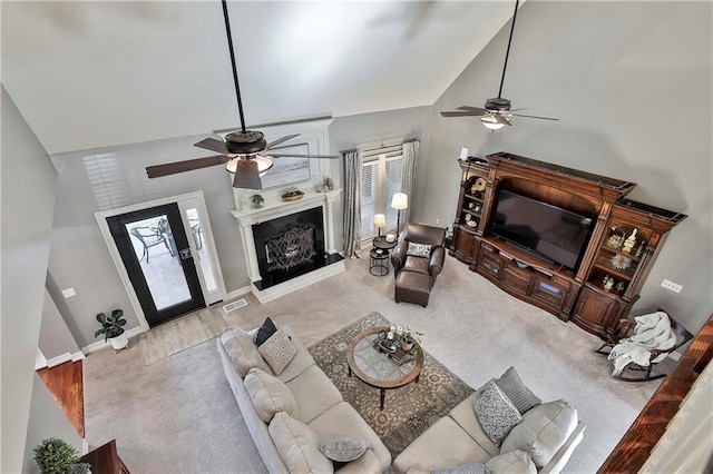 living room featuring ceiling fan, high vaulted ceiling, baseboards, a fireplace, and carpet