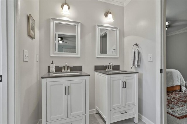 bathroom featuring ornamental molding, two vanities, ensuite bathroom, ceiling fan, and baseboards