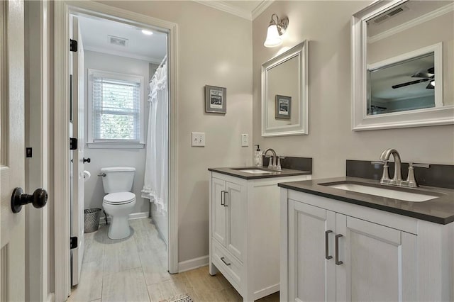 full bathroom with two vanities, ornamental molding, baseboards, and toilet