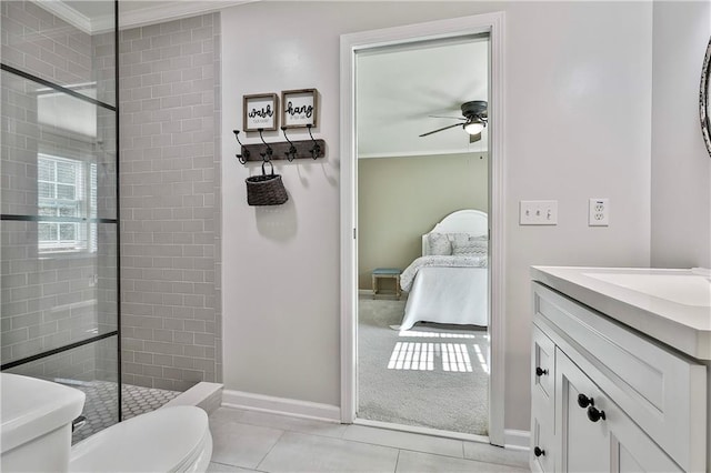 ensuite bathroom with a tile shower, crown molding, ceiling fan, toilet, and baseboards