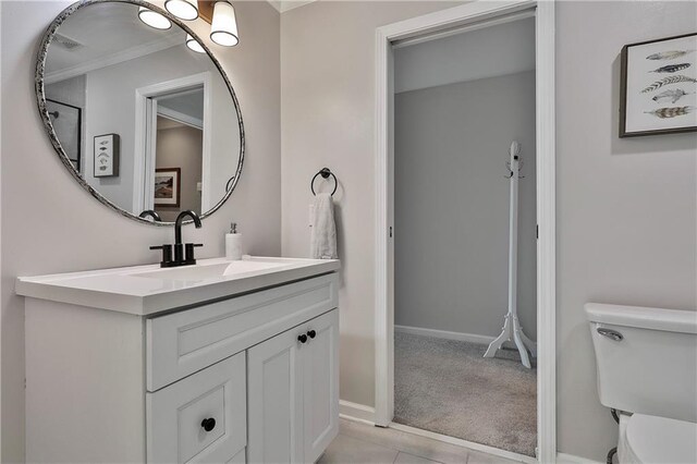 bathroom with toilet, ornamental molding, vanity, and baseboards