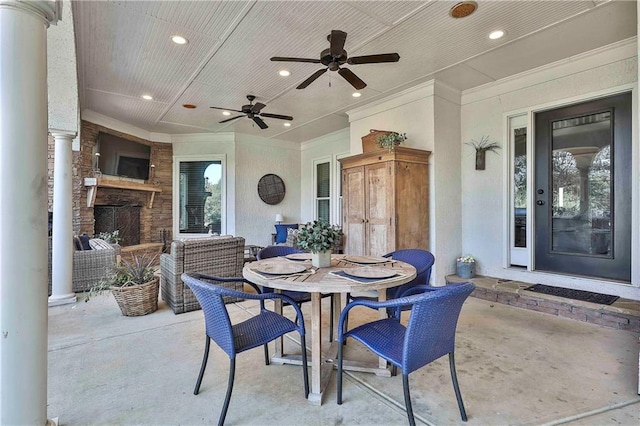 view of patio with outdoor dining space, an outdoor stone fireplace, and a ceiling fan