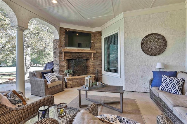 living room with an outdoor stone fireplace, a textured wall, and ornamental molding