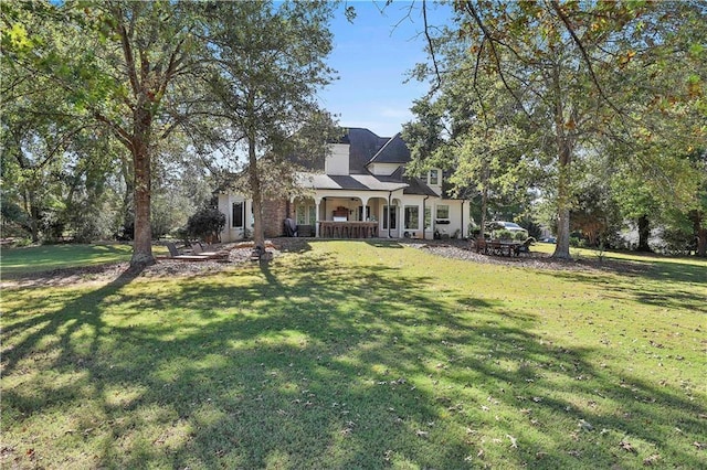 view of front of home featuring a front yard, covered porch, and a chimney