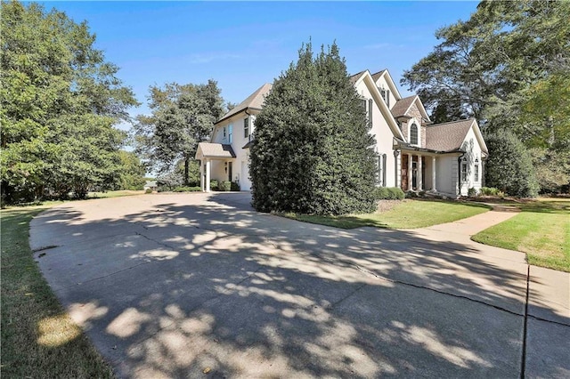 view of side of property featuring stucco siding, concrete driveway, and a lawn