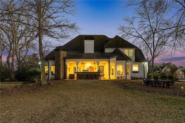 rear view of house featuring a yard and stucco siding