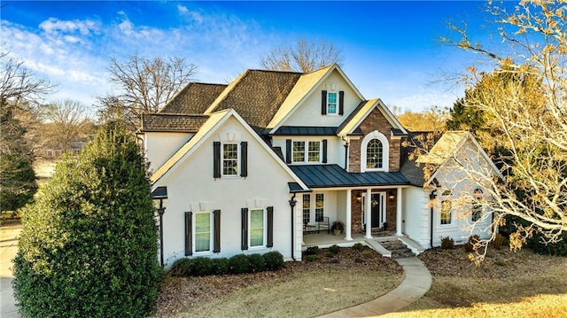 traditional home featuring a standing seam roof, a porch, metal roof, and stucco siding