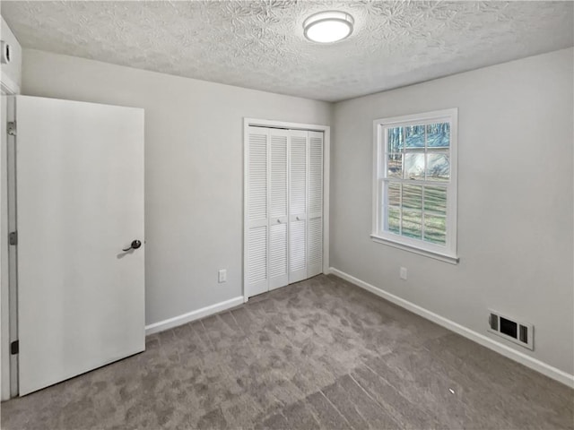 unfurnished bedroom with light colored carpet, a closet, and a textured ceiling