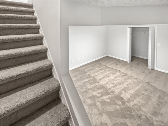 staircase featuring carpet floors and a textured ceiling