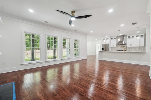 unfurnished living room with crown molding, ceiling fan, dark hardwood / wood-style flooring, and a wealth of natural light