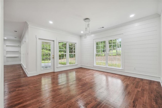 unfurnished room with crown molding, wooden walls, dark hardwood / wood-style floors, and a wealth of natural light