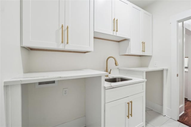 clothes washing area with cabinets and sink