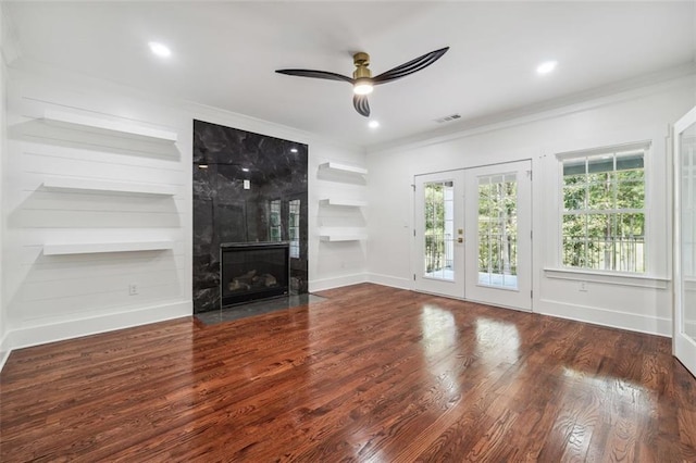 unfurnished living room with built in shelves, a large fireplace, dark hardwood / wood-style floors, and french doors