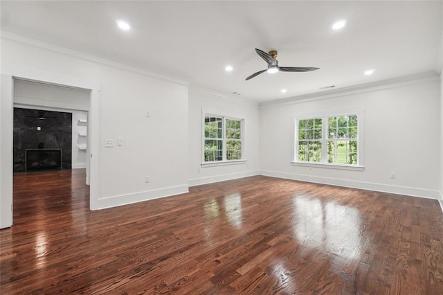 spare room featuring dark hardwood / wood-style flooring, ornamental molding, a tile fireplace, and ceiling fan