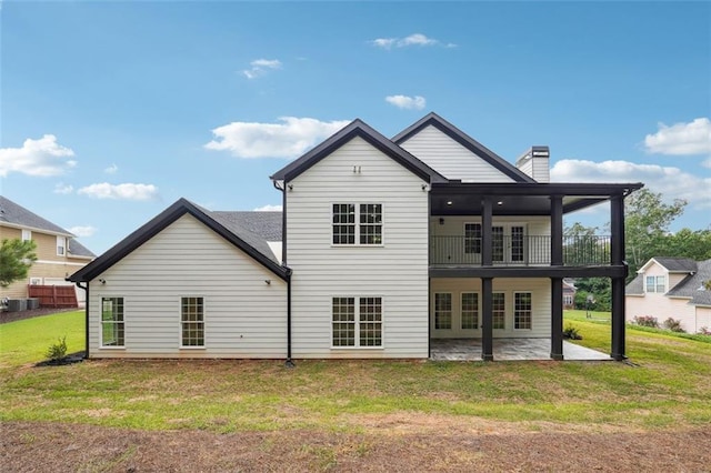 rear view of property featuring central AC, a balcony, a lawn, and a patio area