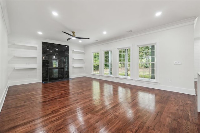 unfurnished living room featuring crown molding, a high end fireplace, dark wood-type flooring, and built in shelves