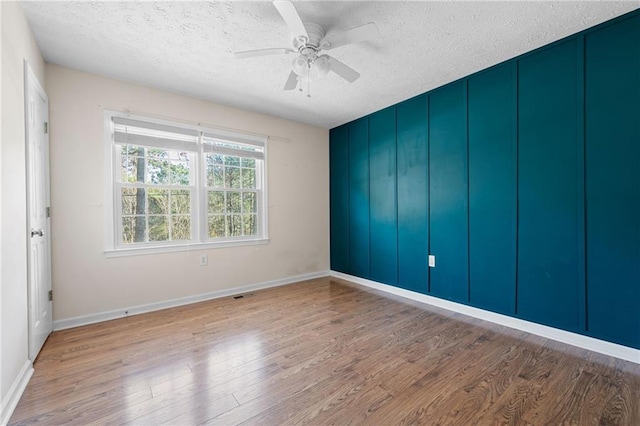 unfurnished room featuring ceiling fan, light hardwood / wood-style floors, and a textured ceiling