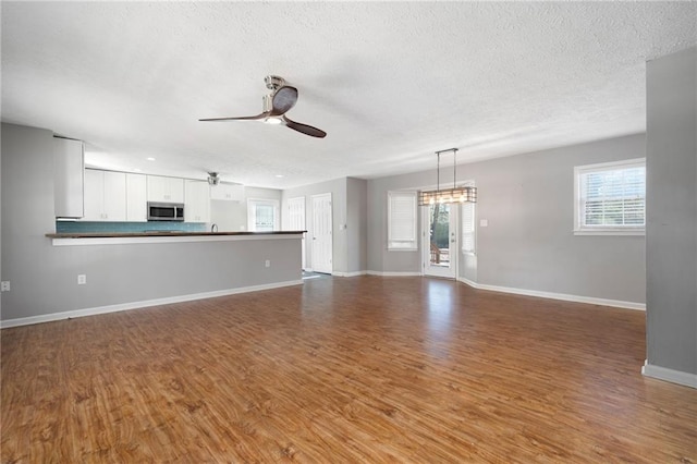 unfurnished living room featuring a textured ceiling, hardwood / wood-style floors, and plenty of natural light