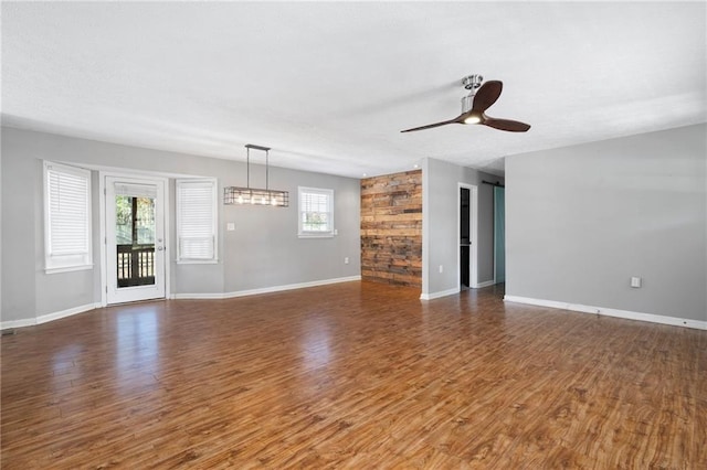 unfurnished room with ceiling fan, a healthy amount of sunlight, and dark wood-type flooring