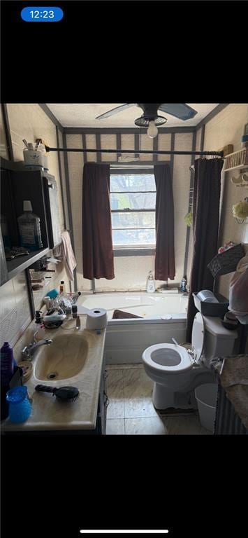 full bath featuring toilet, a tub, vanity, and a ceiling fan