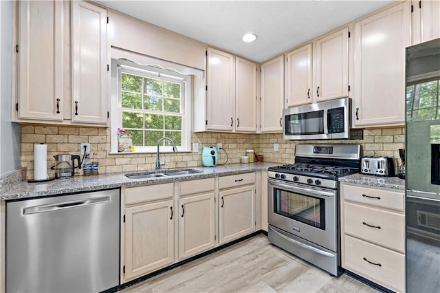 59 Cedar Way, Dallas, GA 30132 - kitchen with stainless steel appliances, a sink, decorative backsplash, light wood finished floors, and light stone countertops