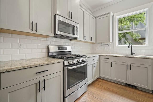 2093 Callaway Ct NW, Atlanta, GA 30318 - kitchen with appliances with stainless steel finishes, a sink, ornamental molding, backsplash, and light stone counters