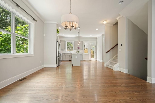 2093 Callaway Ct NW, Atlanta, GA 30318 - unfurnished living room featuring a chandelier, crown molding, stairs, baseboards, and light wood-style flooring