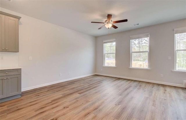 unfurnished room featuring light wood-type flooring, visible vents, baseboards, and ceiling fan