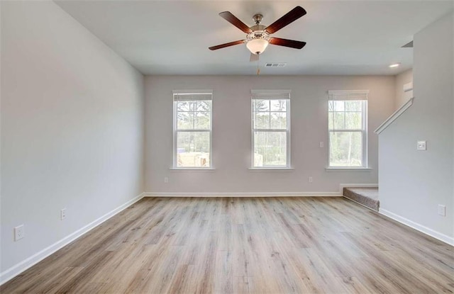 spare room featuring a ceiling fan, wood finished floors, baseboards, and visible vents