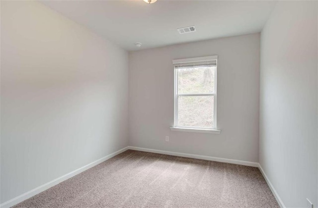 carpeted spare room featuring visible vents and baseboards