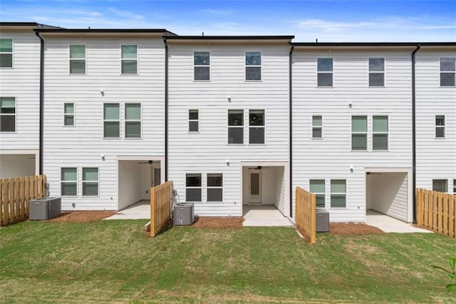 rear view of property with cooling unit, a lawn, and fence