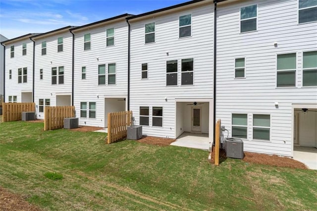 rear view of house with a yard, central AC, and fence