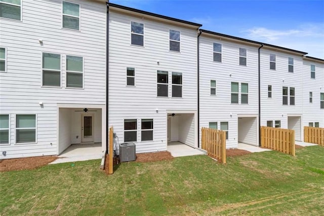 back of property featuring central AC unit, a lawn, a patio, and fence