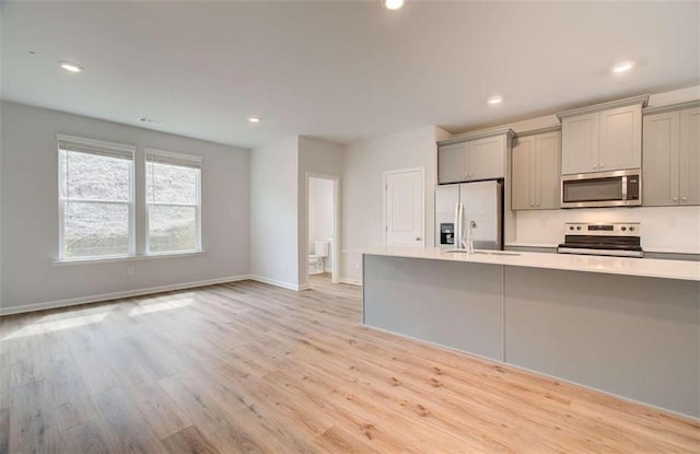 kitchen featuring light wood finished floors, recessed lighting, gray cabinets, stainless steel appliances, and light countertops