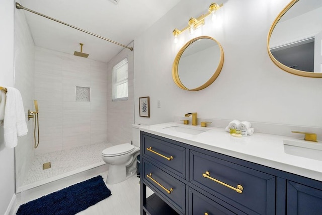 bathroom with vanity, toilet, and a tile shower