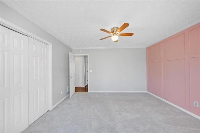 unfurnished bedroom featuring ceiling fan, crown molding, light colored carpet, and a textured ceiling