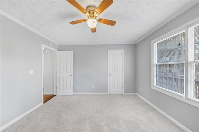 carpeted spare room featuring ceiling fan, plenty of natural light, a textured ceiling, and ornamental molding