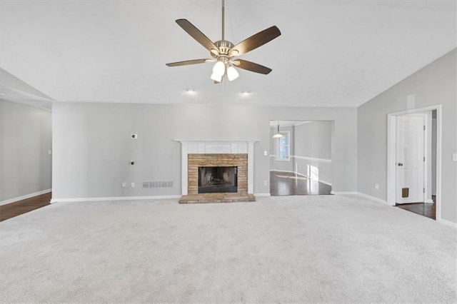 unfurnished living room with a brick fireplace, ceiling fan, dark carpet, and vaulted ceiling