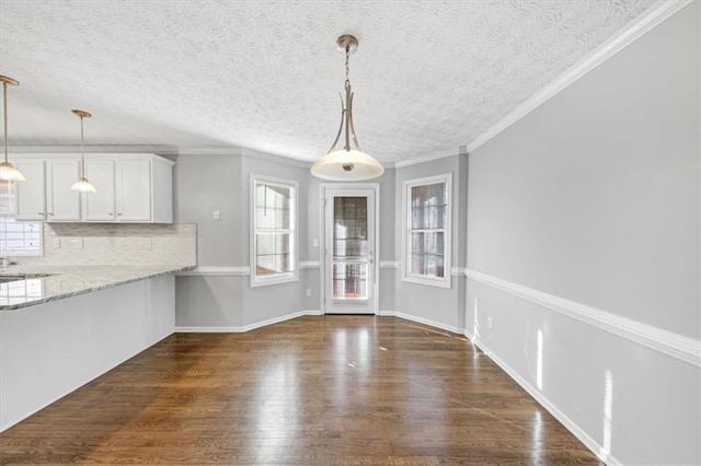 unfurnished dining area with a textured ceiling, dark hardwood / wood-style flooring, and crown molding