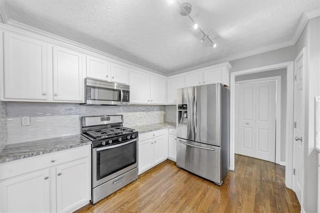 kitchen with stainless steel appliances, white cabinetry, tasteful backsplash, and light hardwood / wood-style floors