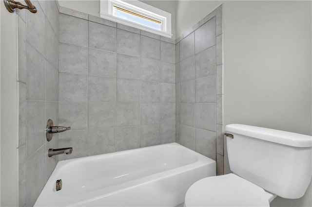 bathroom featuring tiled shower / bath combo and toilet