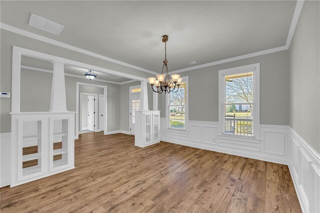 unfurnished dining area featuring crown molding, hardwood / wood-style floors, and a notable chandelier