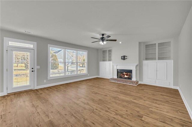 unfurnished living room featuring plenty of natural light, ceiling fan, and built in features