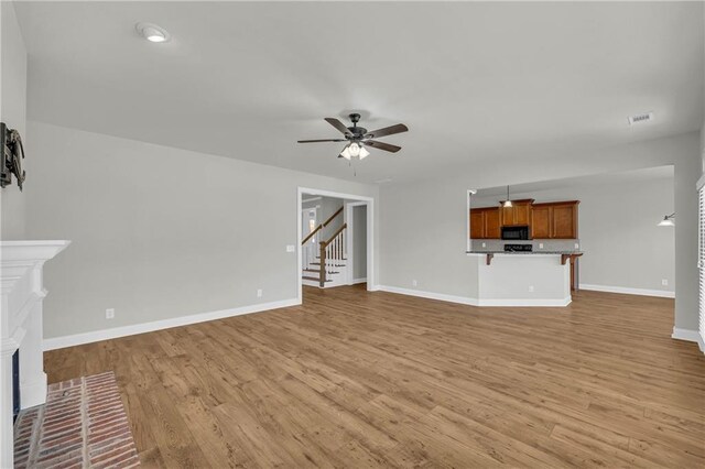 unfurnished living room featuring a fireplace, light wood-type flooring, and ceiling fan