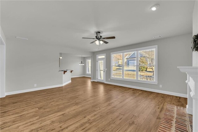 unfurnished living room with ceiling fan, a fireplace, and hardwood / wood-style floors